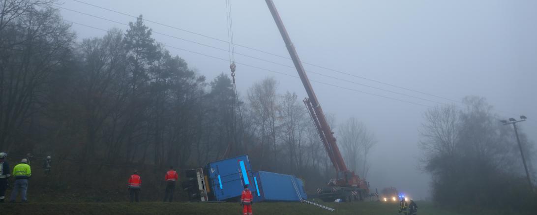Das Bild zeigt einen Kran, welcher einen umgekippten LKW hebt.