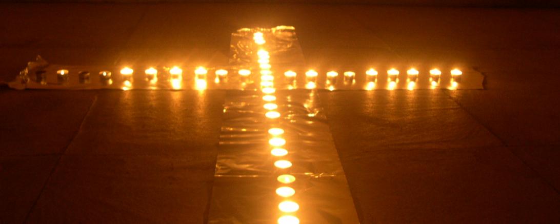 Kerzen bilden ein Kreuz auf dem Boden vor einem Altar