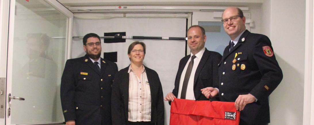 Bettina Wegner-Bock (Brandschutzbeauftragte gKU) und Jochen Kirchner (Leiter Wirtschaftsabteilung gKU) überreichten die neue Ausrüstung an die Kommandanten Marco Kurz und Andreas Tegeler.