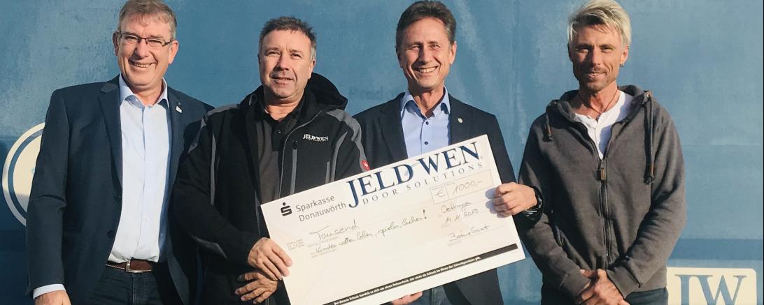 Vier Männer mit Scheck bei einer Spendenübergabe
