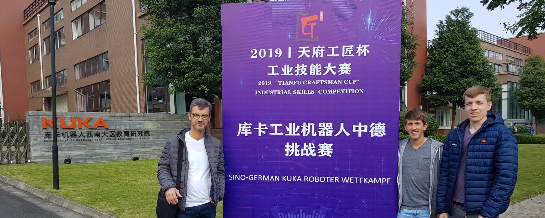 Josef Wolf, Richard Haas und Florian Knie stehen vor einem Schild mit chinesischen Schriftzeichen