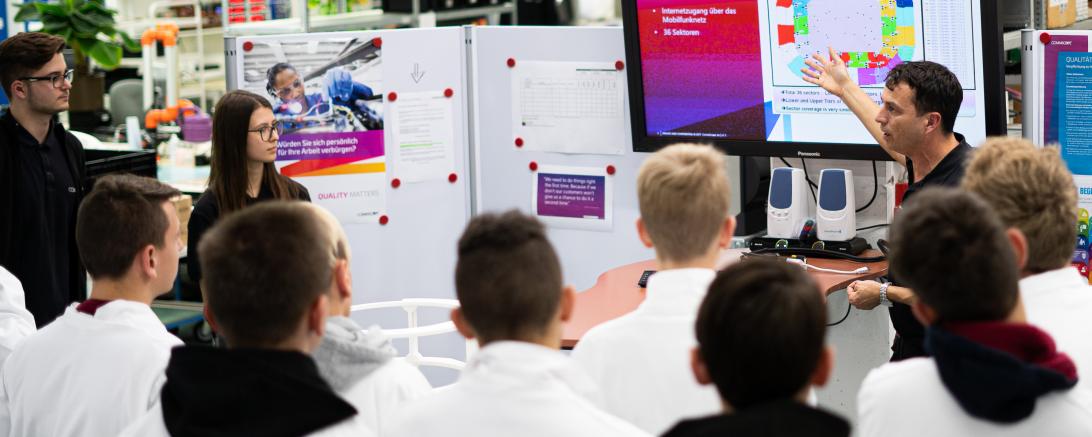 Das Bild zeigt v.l.n.r. Simon Reil, Laura Reitsam (Azubis bei Andrew) und Klaus Osterrieder (Andrew), sowie Gruppe von Schülern. 