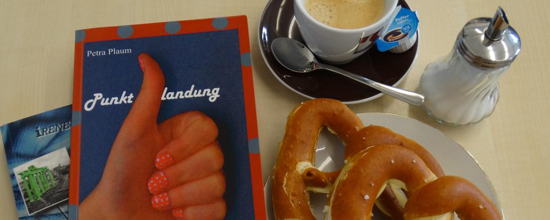 Das Bild zeigt Bücher mit Kaffee und Brezen.