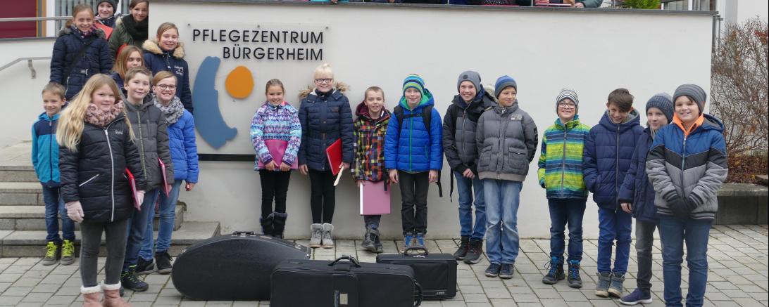 Das Bild zeigt die Schülerinnen und Schüler der Klasse 5a bei ihrem Besuch vor dem Bürgerheim mit den verantwortlichen Lehrkräften Birgitta Möckel und Helmut Radeck. 