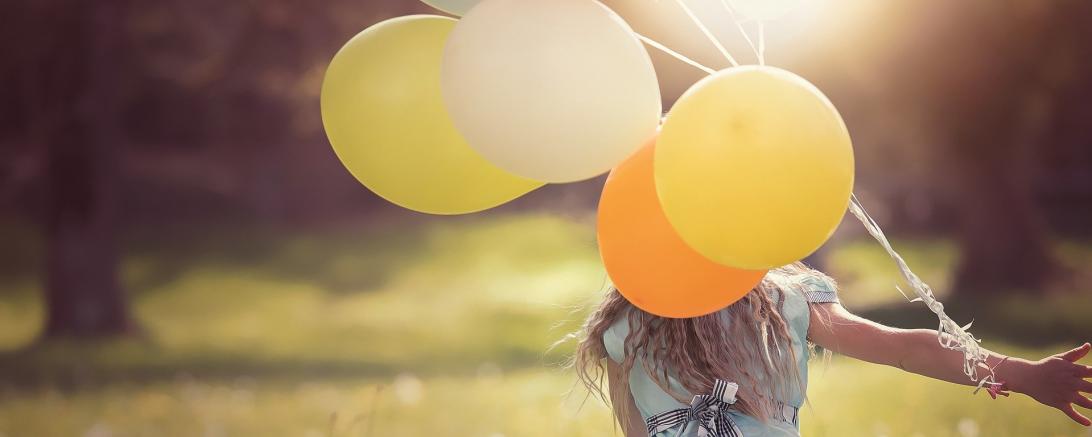 Das Bild zeigt ein Mädchen mit Luftballons