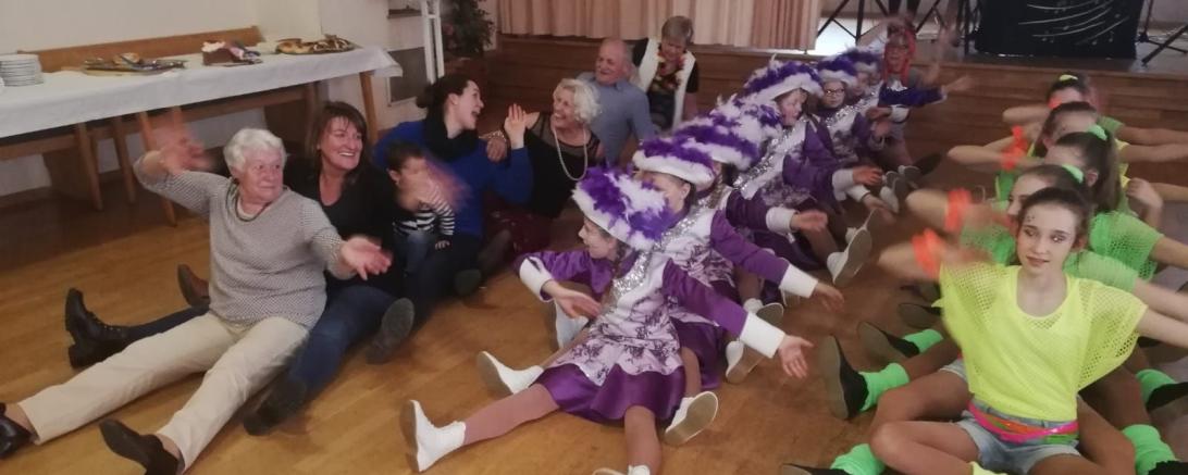 Senioren und Tanzgarde sitzen auf dem Boden
