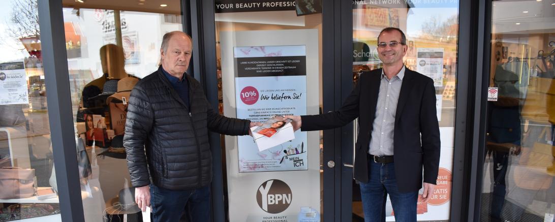 Übergabe des ersten Päckchens durch Jo Tomaschewski (rechts) von der Top Parfümerie, an Robert Schuck, Fahrdienstkoordinator des Caritasverbands.