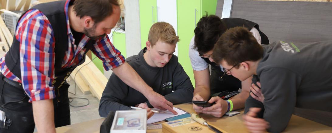 Das Bild zeigt Auszubildende der Schreinerei Stark in Auhausen die zusammen mit ihrem Lehrmeister ein Projekt erarbeiten.