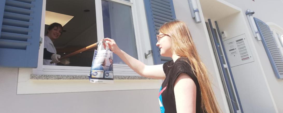 Apothekerin gibt Medikamente durchs Fenster an Kundin