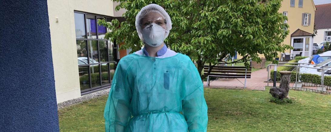Das Bild zeigt Jaqueline Trost in Schutzausrüstung an ihrem Arbeitsplatz der Diakonie in Harburg. 