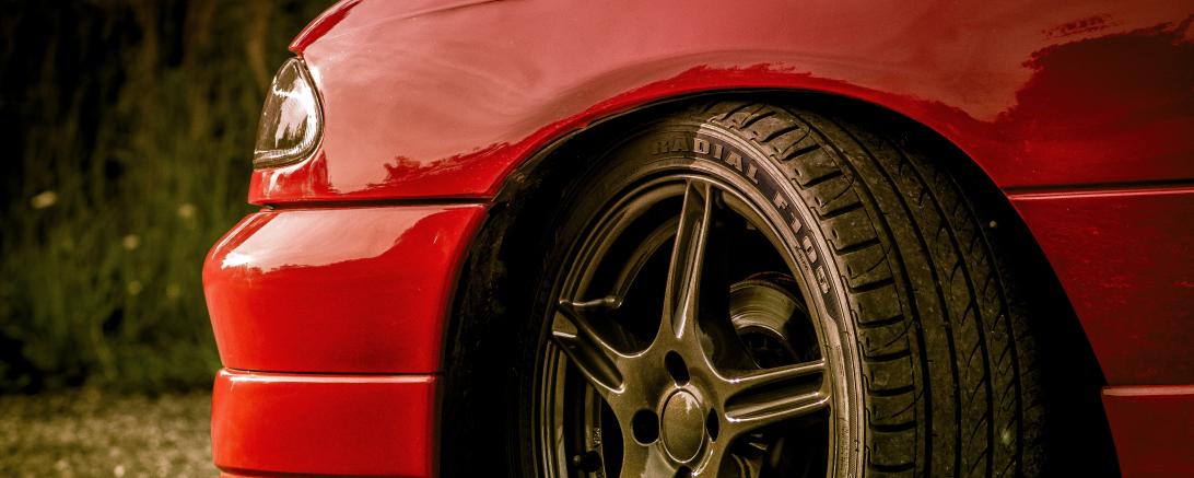 Linke Vorderseite eines roten Autos mit Alufelge