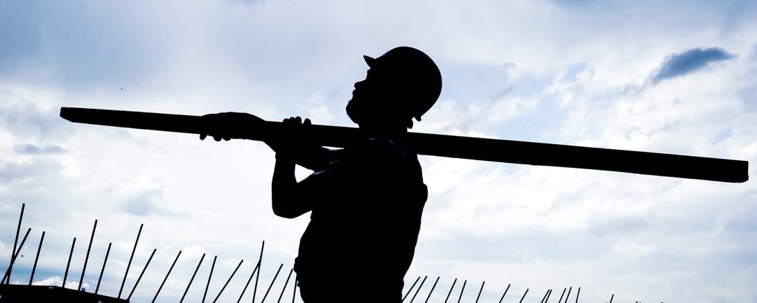 Schatten eines Bauarbeiters mit Helm und Holzlatte