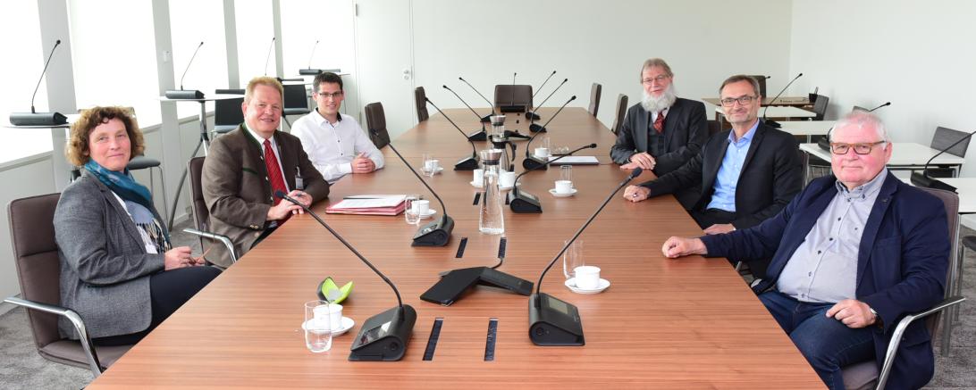 Sechs Personen sitzen an einem Konferenztisch