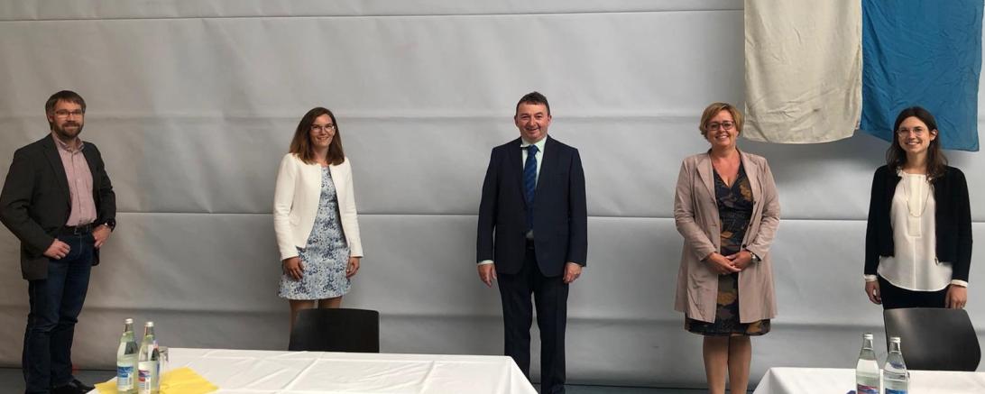 Fünf Personen vor Turnhallentrennwand