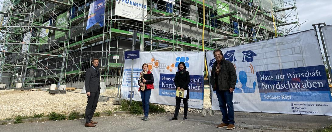 Vier Personen vor eingerüstetem Büroneubau