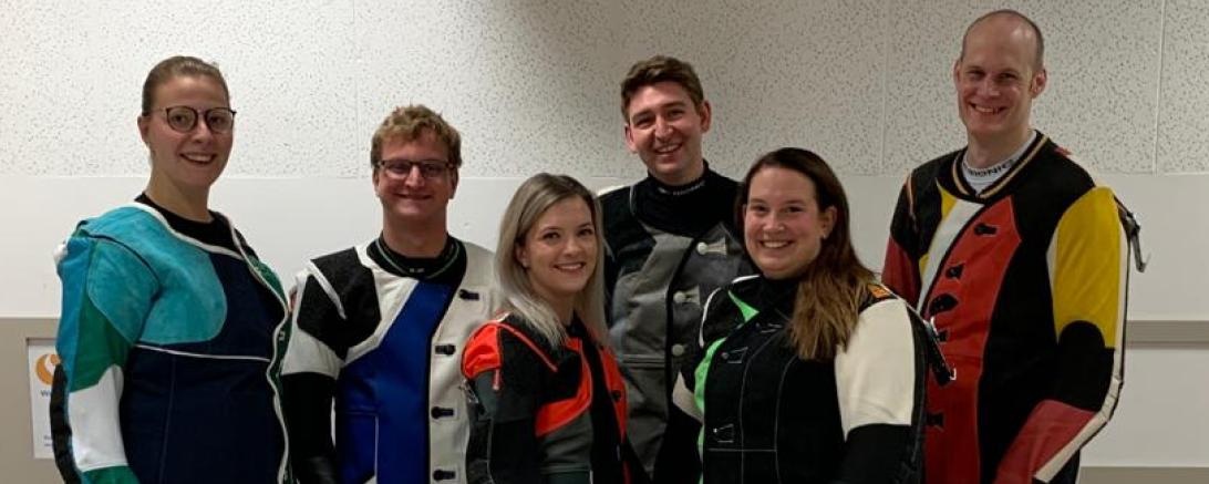 Sechs Sportschützen im Anzug