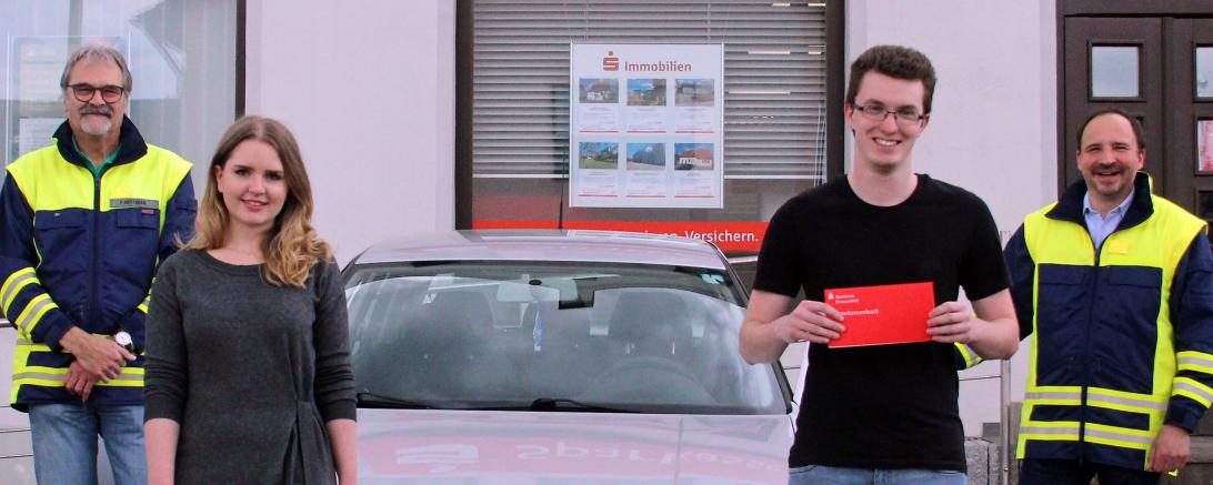 Bild zeigt im Vordergrund die Leiterin der Geschäftsstelle Tapfheim der Sparkasse Donauwörth, Nadja Beck, bei der Übergabe des Sparbuchs an Maximilian Schreiber. Dahinter links von der Gebietsverkehrswacht Donauwörth der lokale Projektleiter von „Könner durch Erfahrung“, Peter Oesterer sowie rechts der Vorsitzende Karl Würth.