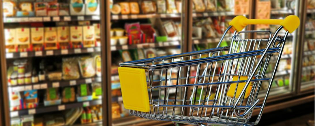 Einkaufswagen vor Supermarktregalen