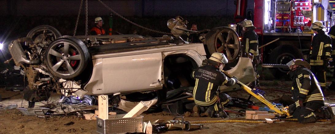 Zerstörter Pkw mit Feuerwehrleuten