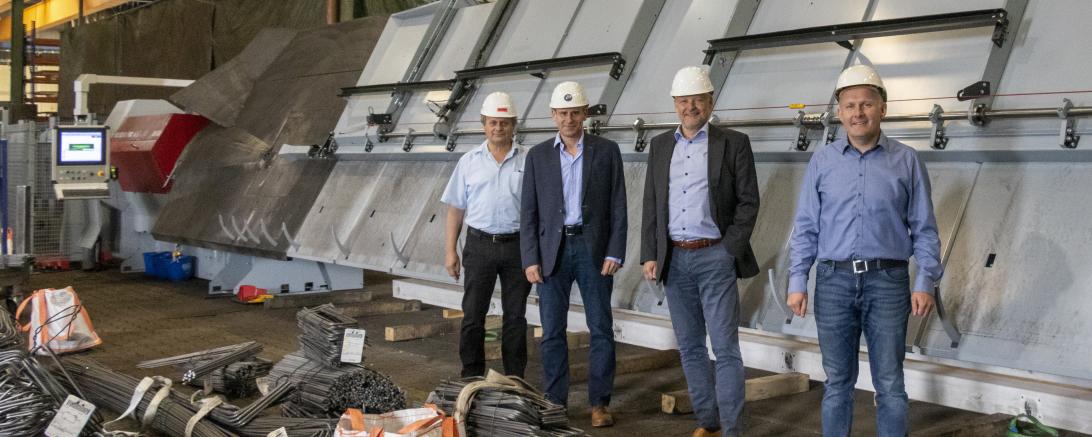 Ein neuer, energiesparender Bügelbiegeautomat ist seit kurzem im Biegebetrieb von Eisen-Fischer in Nördlingen für die Bearbeitung von Betonstahl im Einsatz. Über diesen Meilenstein freuen sich vor der neuen Maschine von links Wilhelm Uhl vom Facility Management, Betonstahl-Gruppenleiter Friedrich Engelhard, Geschäftsführer Volker Baumgärtner und Biegebetriebs-Gruppenleiter Rainer Schmidt.