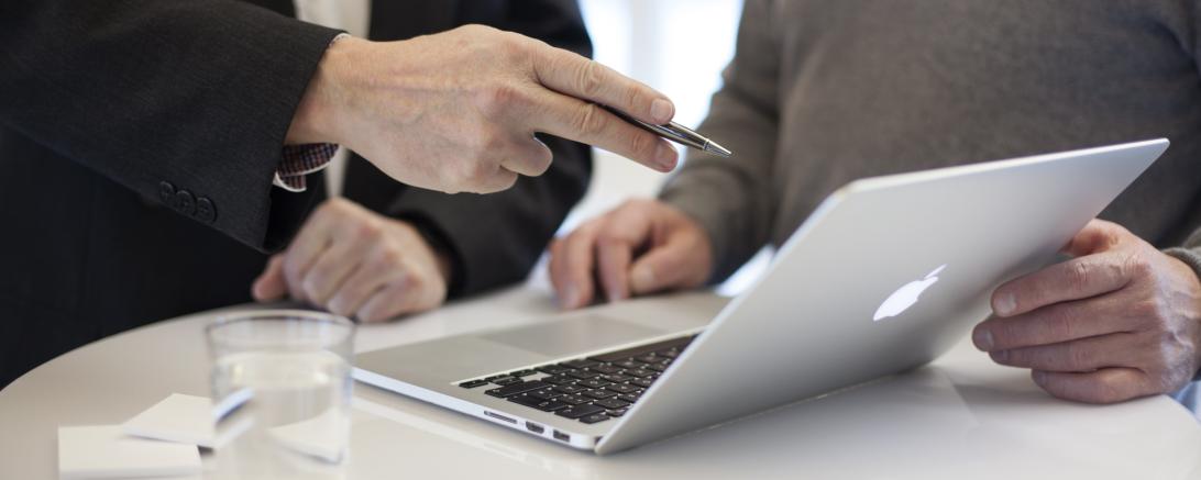 Zwei Männer an einem Stehtisch mit Laptop