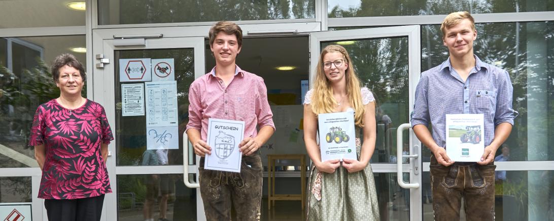 Lehrerin mit drei Landwirtschaftsschulen-Absolventen in Tracht, mit Urkunden