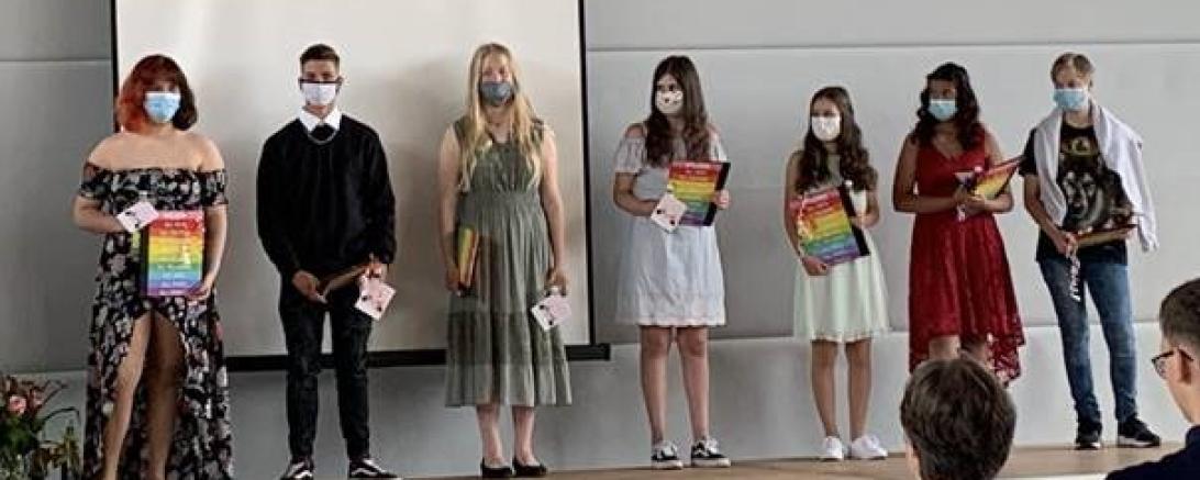 Sieben Abschlussschüler mit Masken und Zeugnissen
