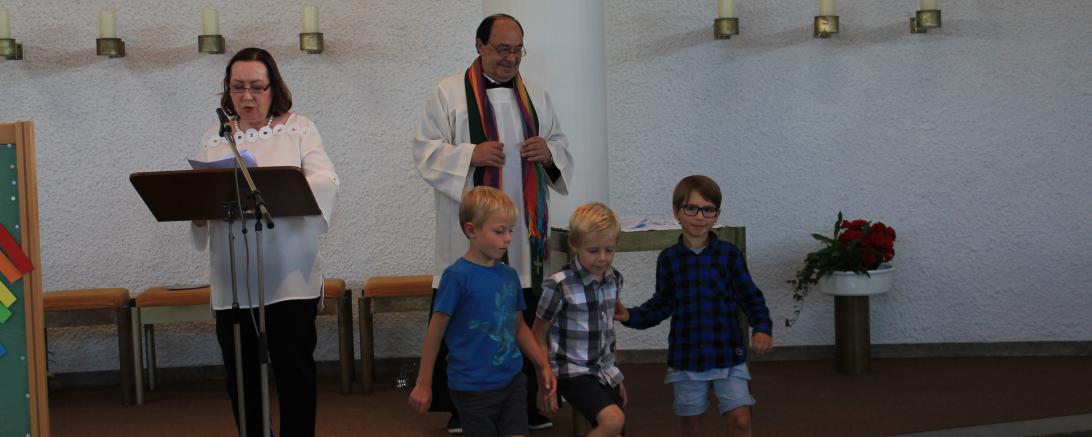 Drei Kinder mit Pfarrer und eine Rednerin