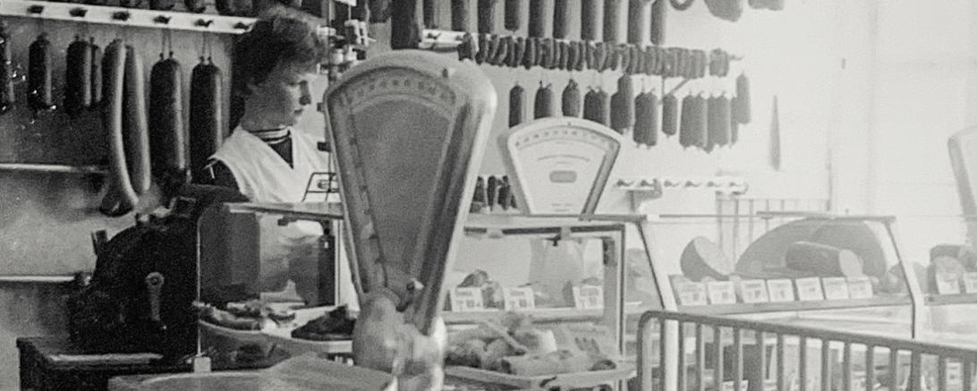 Schwarzweißaufnahme einer Fleischtheke mit Verkäuferin