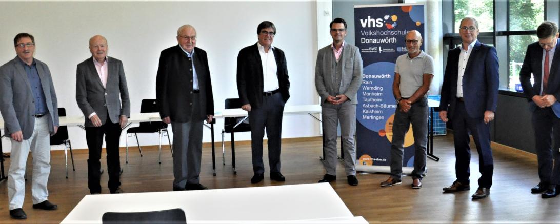 Acht Männer mit Sicherheitsabstand vor Roll-up der VHS Donauwörth