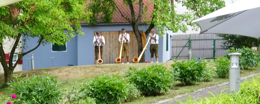 Zwei Senioren hören drei Alphornbläsern zu