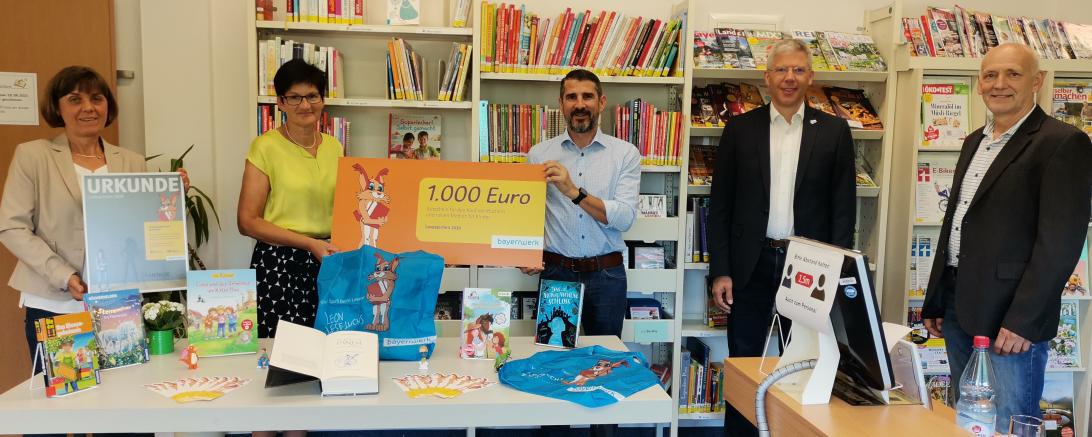 Fünf Personen stehen mit Scheck in Bücherei