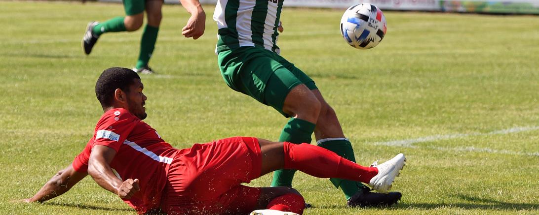 Zwei Fußballer im Zweikampf, einer grätscht