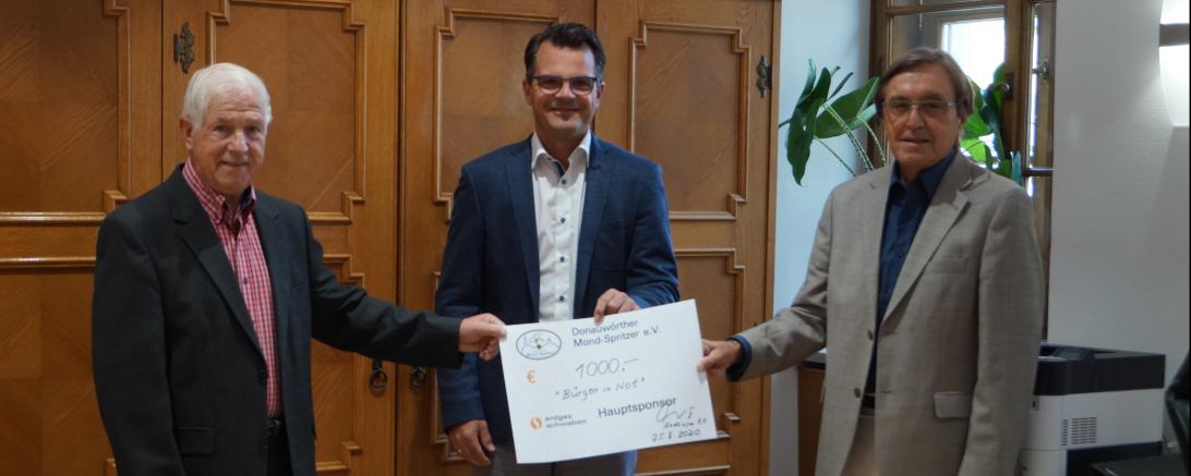 Drei Herren mit Scheck vor Holzschrank