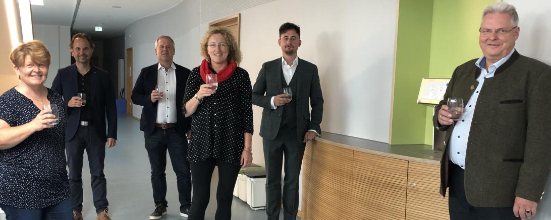 Personen mit Glas in der Hand stehen in einem Flur