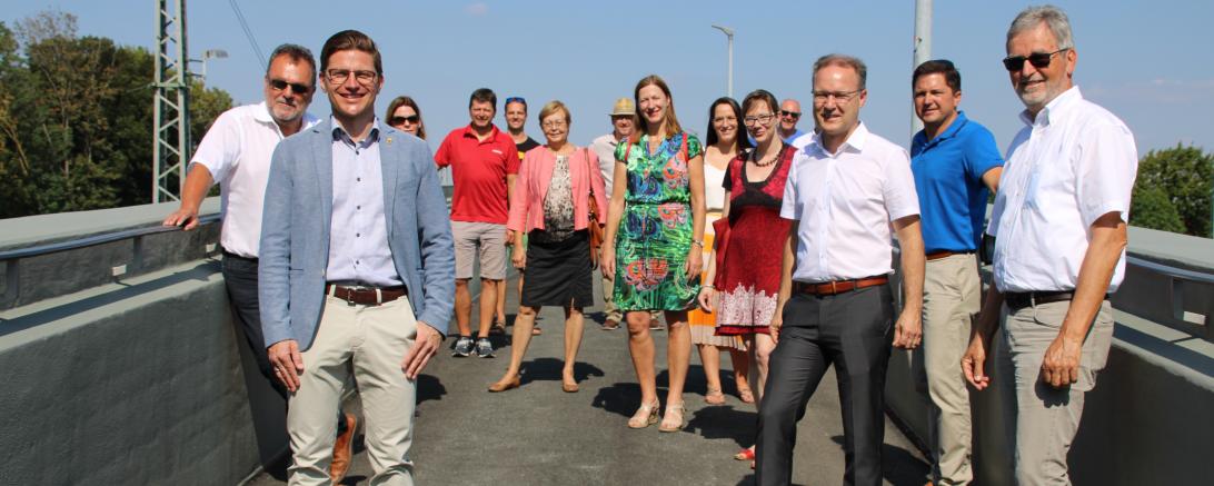 14 Personen stehen mit Abstand auf einer Brücke
