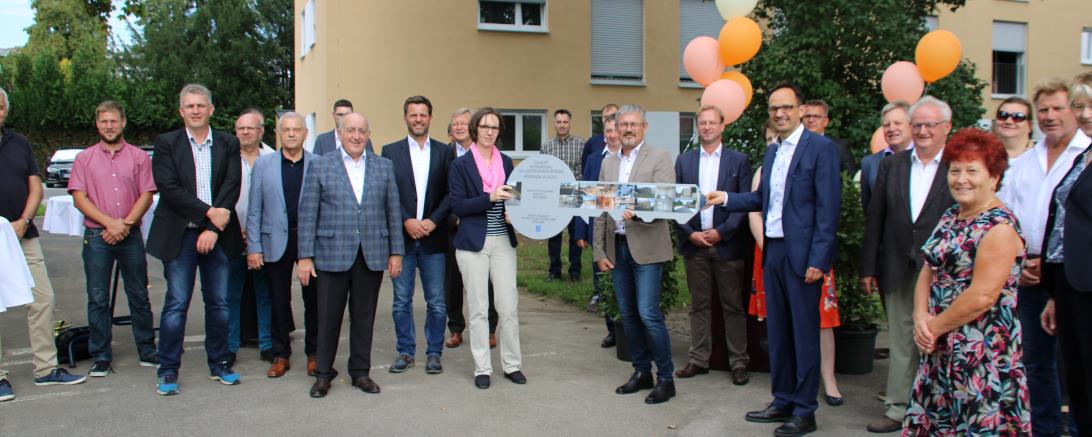 Circa 20 Personen bei Schlüsselübergabe vor Mehrfamilienwohnhaus