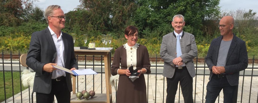 Vier Personen, einer übergibt Auszeichnung an Dame