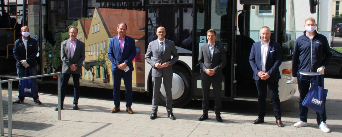 Sieben Männer stehen vor einem Schulbus