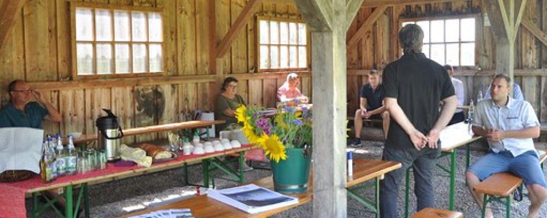 Menschen auf Biertischbänken in Holzgebäude