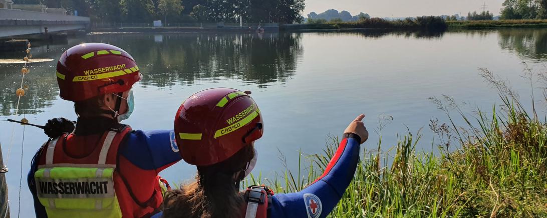 Das Bild zeigt zwei Wasserretter, die die örtlichen Gegebenheiten erkunden und achten auf mögliche Gefahrenquellen.