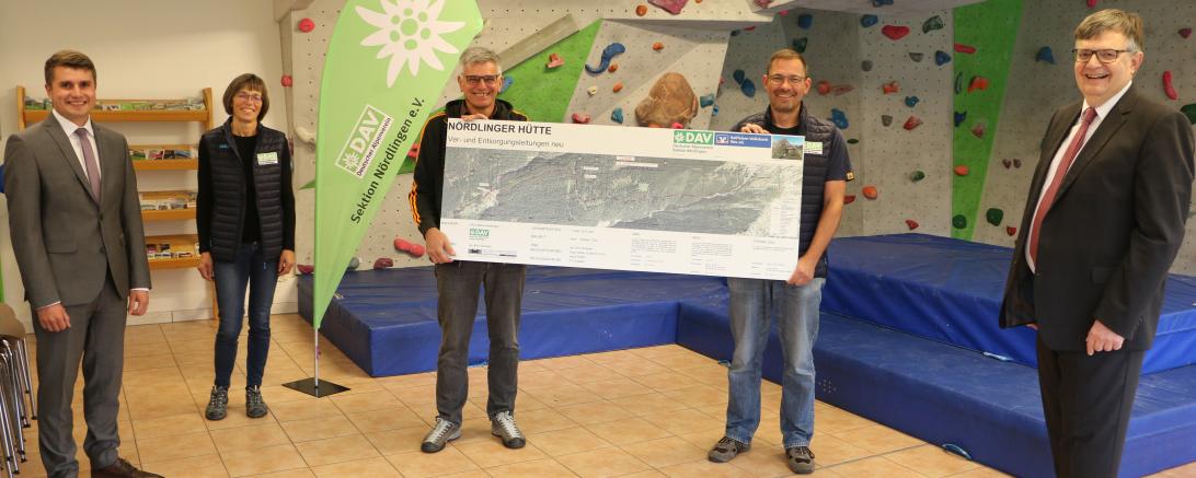 Fünf Personen vor Boulderwand mit Projektinfo Versorgungsleitungen Nördlinger Hütte