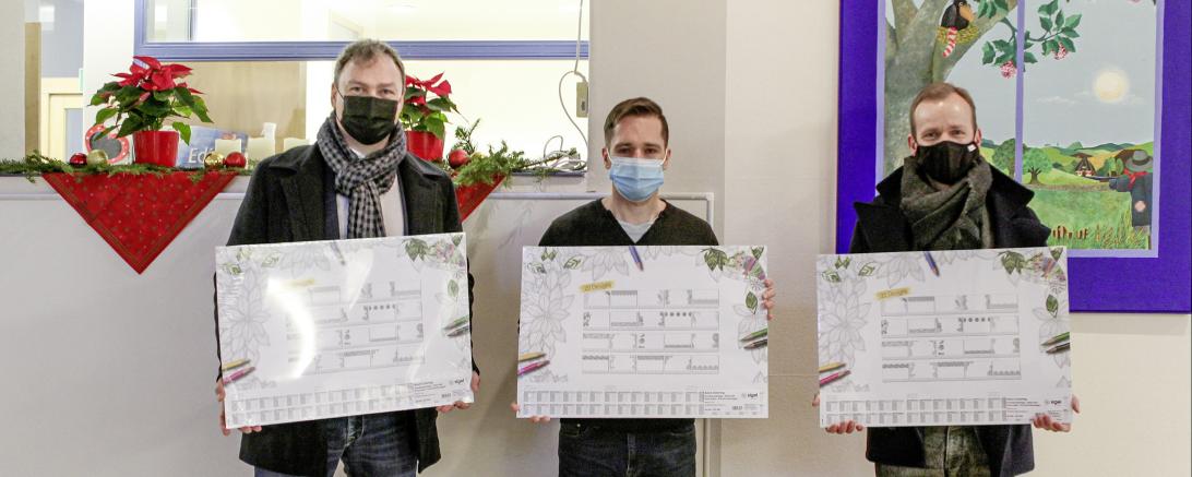 Daniel Petrasch (l.) und Götz Stamm (r.) von der SIGEL GmbH überreichen Jörg Speer (M.) die Schreibunterlagen. Der Leiter der Kindertagesstätte St. Martin in Mertingen freute sich sehr über das Geschenk.