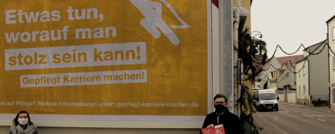 Julia Lux und Stefan Rößle mit Maske vor Plakat der Gesundheitsregionplus Donauries