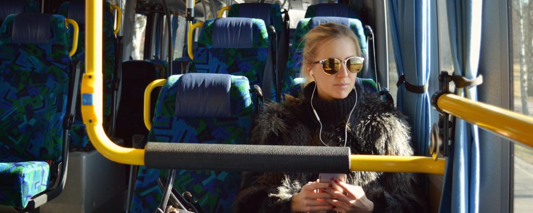 Frau mit Sonnenbrille sitzt im Bus