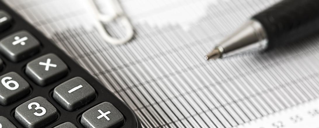 Taschenrechner und Kugelschreiber auf liniertem Papier