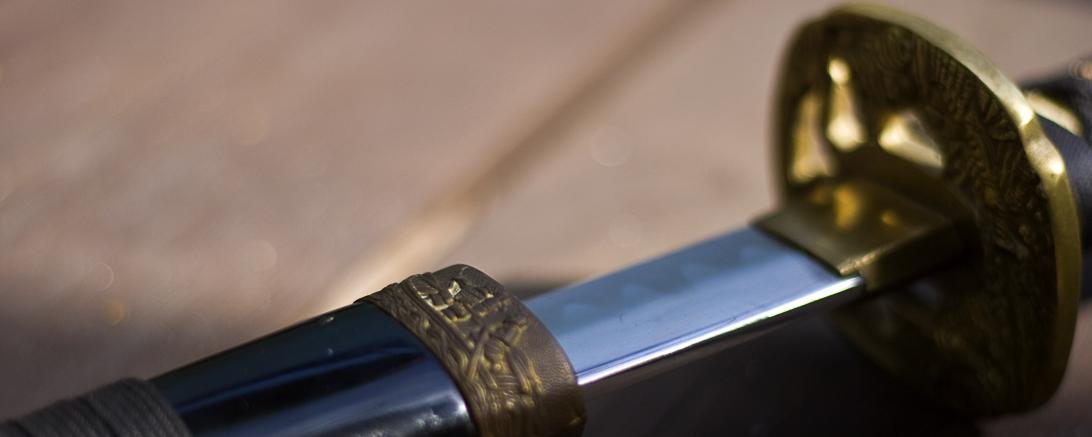 Katana liegt auf einem Holztisch, ein Stück aus der Scheide gezogen