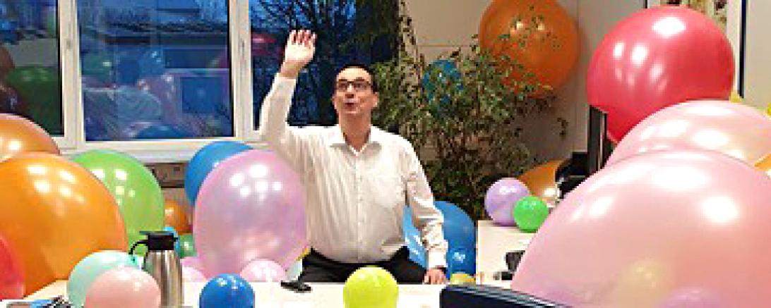 Mann in Büro voller Luftballons