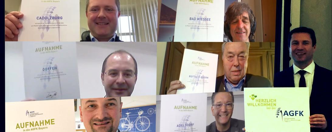 Mann vor Bildschirm mit Videokonferenz mit sechs Teilnehmern, alle halten AGFK-Aufnahme-Urkunde hoch