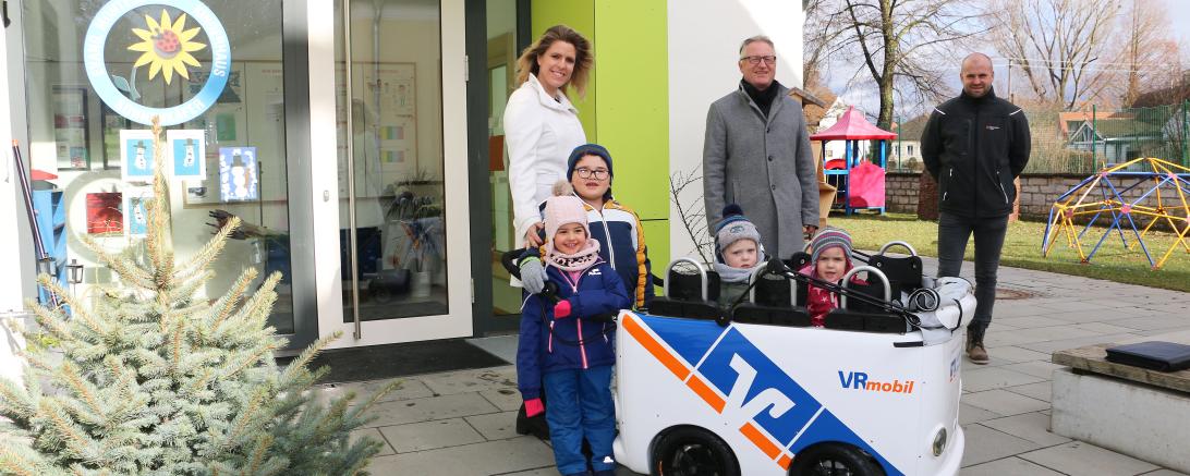 Einrichtungsleiterin Andrea Engelhard, Werner Feil (RVB Ries) und Elternbeiratsvorsitzender Rene Steinmeyer mit Kindern vor dem Montessori-Kinderhaus in Löpsingen. 